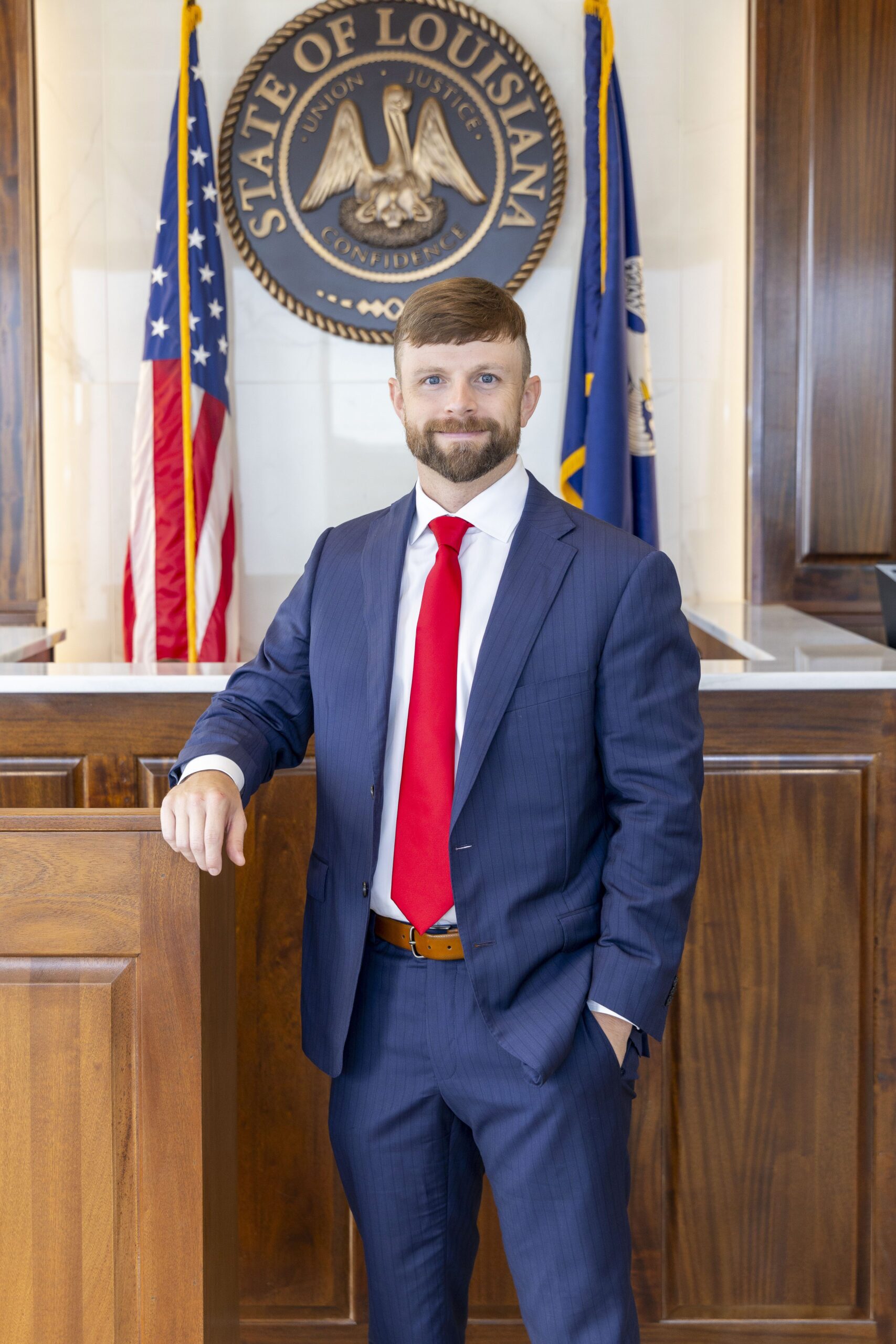 A man in a blue suit and red tie stands at a Louisiana podium, representing car accident attorneys.