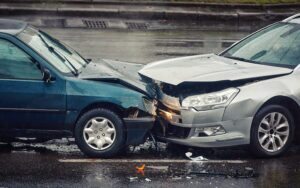 Car accident on wet road during rain, head on collision side view. Two cars damaged after head-on collision.