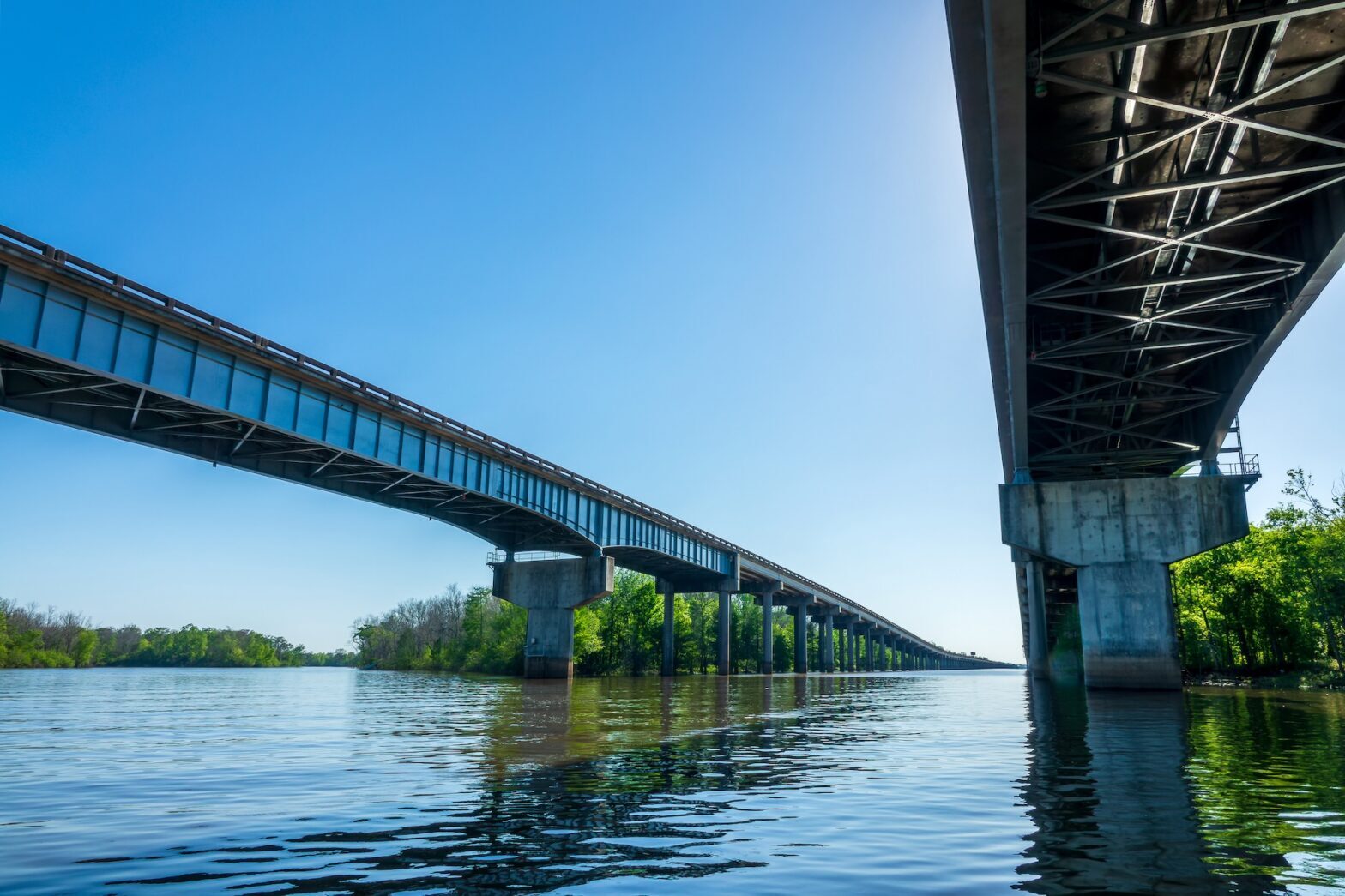 Two parallel Lafayette bridges spanning a calm river under a clear sky
