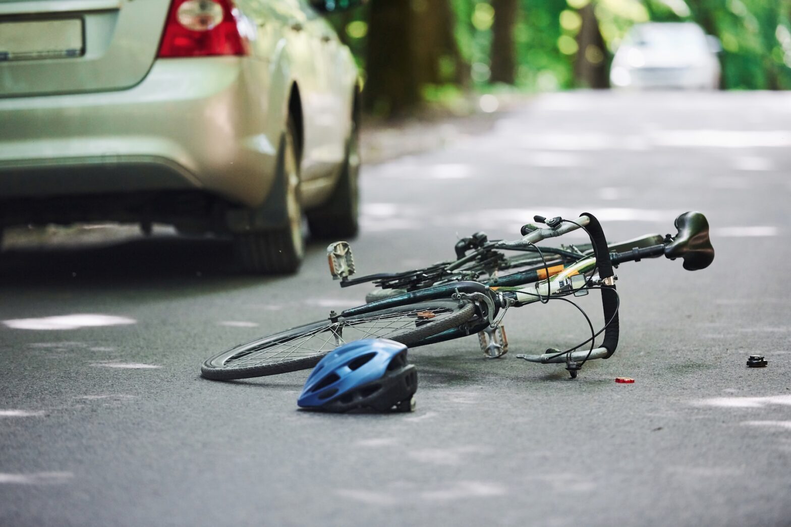 A bicycle and helmet on the road next to a parked car in New Orleans, suggesting an accident
